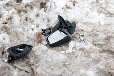 Pieces of a car mirrors after an accident on dirty snowの写真素材