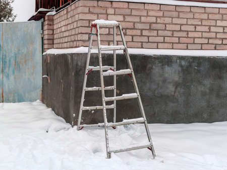an aluminum ladder abandoned in the snowy backyard, winter scene