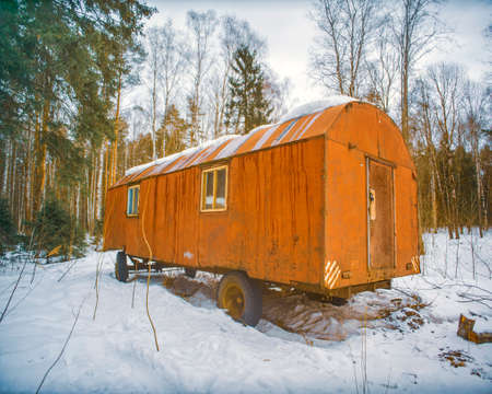 abandoned old rusty metal trailer in a winter forest, daylight shotの写真素材