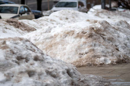 melting dirty snowdrifts in the end of winter, city sceneの写真素材