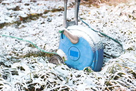 a frozen mobile watering cart abandoned in a garden, winter sceneの写真素材
