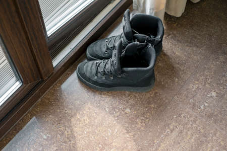 a pair of boots left next to an entrance door, indoor shot