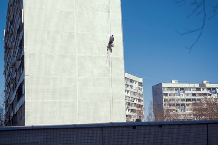 industrial alpinist during plaster works on a building tiled facade, outdoor shot