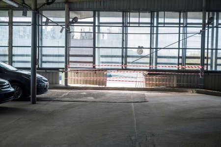 a warning tape around a hole in the wall of parking, indoor contra light shot