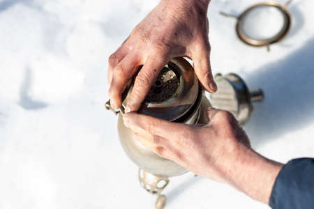 male hands disassembling vintage silver plated coffeemaker, outdoor winter shotの写真素材