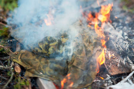 closeup of a burning camouflage uniform in fire, outdoor shotの写真素材