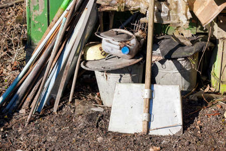 A shovel and discarded household stuff abandoned in a backyardの写真素材