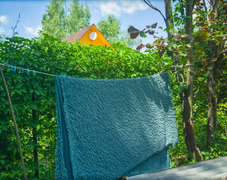 blue fluffy carpet hanging on a rope, summertime outdoor imageの写真素材