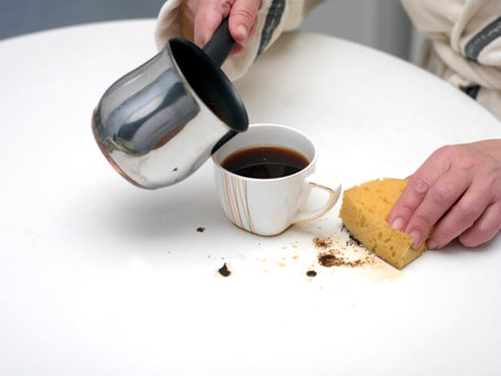 Woman and just spilled coffee on the table, indoor close upの写真素材