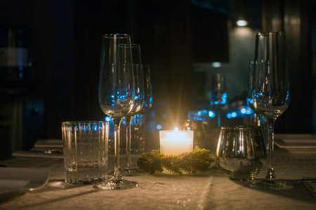 a candle and a bunch of empty wineglasses on the table, night scene