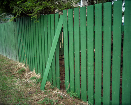 green wooden fence with removed board, concept of insecurityの写真素材