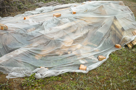 a pile of abandoned on the ground construction materials covered with cellophaneの写真素材