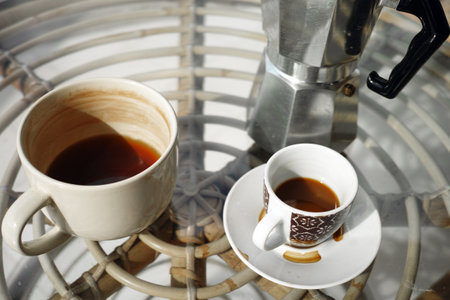 half empty tea mug and coffee cup and pot abandoned on the table after breakfastの写真素材