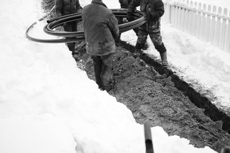a group of workers laying the cable or gas pipe in the trench, in black and whiteの写真素材