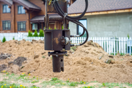 pile driver rig and vacuum hoses in the foreground and houses in the blurred backgroundの写真素材