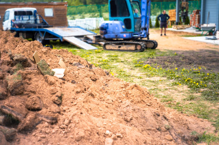 pile of excavated ground and an excavator in the blurred background, outdoor shotの写真素材