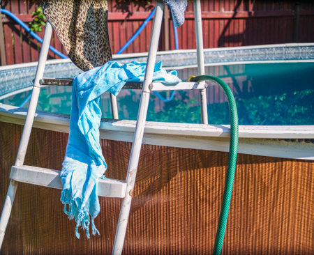 wet clothing drying on an above ground pool ladder, sunny day shot