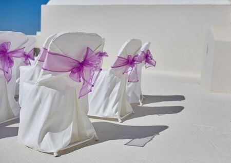 white chairs with purple bows on a white location for a weddingの写真素材