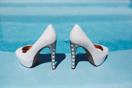white high-heeled shoes are by the poolの写真素材