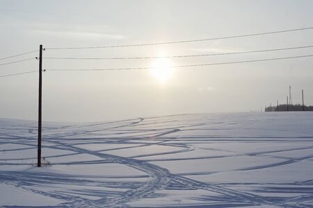 Snow field crossed by tracks from passing carsの写真素材