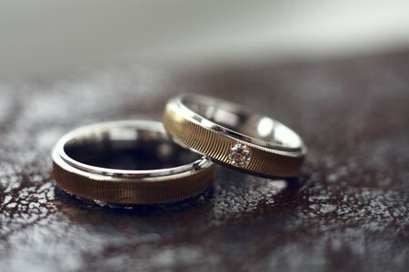 Two gold wedding rings with one diamond. Selected focus on diamondの写真素材
