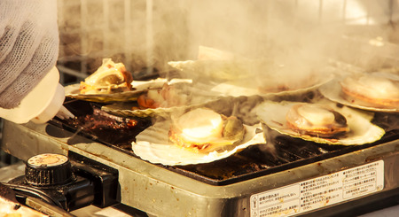 Big fresh scallops charred on the pan ready to be sold in Cherry Blossom Festival in Hakodateの写真素材