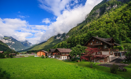Beautiful panoramic postcard view of picturesque rural mountain scenery in the Alps with traditional old alpine mountain chalets and fresh green meadows on a sunny day with blue sky and clouds in the summer.の写真素材