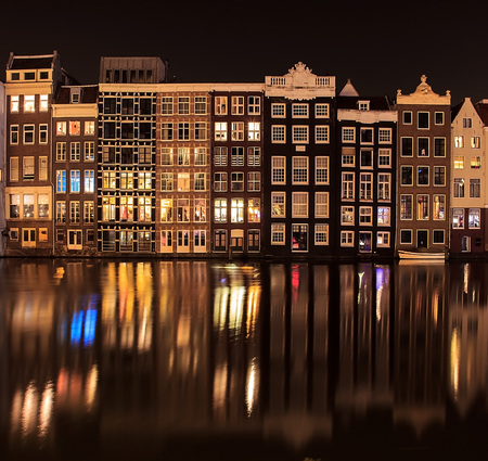 Beautiful traditional old buildings at night with reflection in Amsterdam, the Netherlandsの写真素材