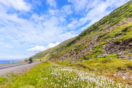 View of motorcyclists ride along scenic coastline and landscape of the Isafjordur fjord or fjord of ice, Westfjords, Iceland, Europe. Abstract: holiday, exploration, fun, competition.の写真素材