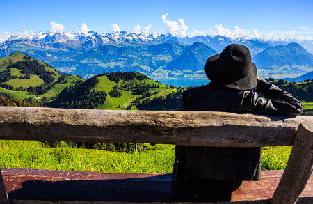 Asian woman on the bench treasures beautiful scenic panoramic view of majestic swiss alps that surrounding Rigi Kulm, the queen of mountains, at Rigi Kulm Station, Lucerne, Switzerland, Europe.の写真素材