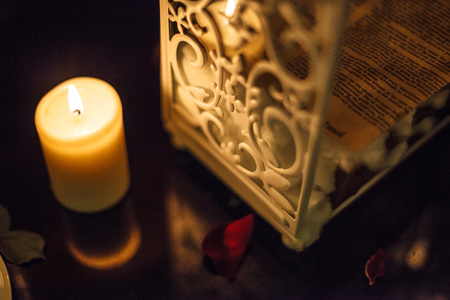 romantic decoration, candle and white beautiful container metal wrought iron box with rose petals on the reflected black marble tableの写真素材