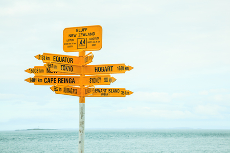 Bluff New Zealand yellow Signpost, with arrows pointing to different directions, major destinations, big cities such as Tokyo, Sydney, New York, Hobart, Kumagawa, Stewart Island, Cape Reinga, Equatorの写真素材
