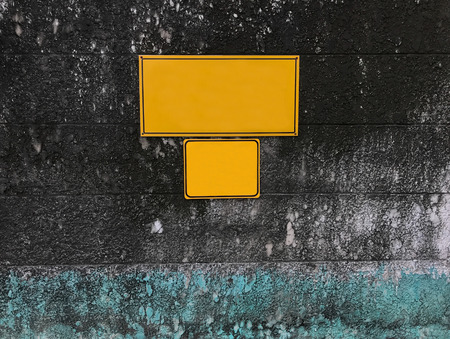 blank empty yellow notice board on mossy aged grunge rough stone wallの写真素材