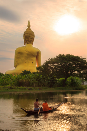 Ang Thong/Thailand - April 8, 2018: A man and monk riding on the rowing boat in the morning to Big Golden Buddha Image at Wat Muang (Muang Buddhist Temple), Ang Thong, Thailandのeditorial素材