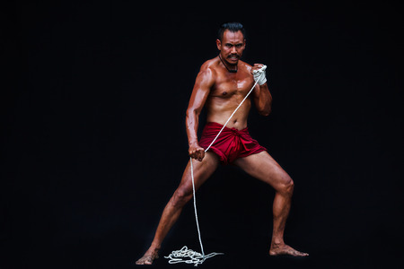 Handsome Muscular Man displays ancient Asian traditional martial arts, Thai Boxing or Muay Thaiの写真素材