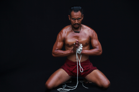 Handsome Muscular Man displays ancient Asian traditional martial arts, Thai Boxing or Muay Thaiの写真素材