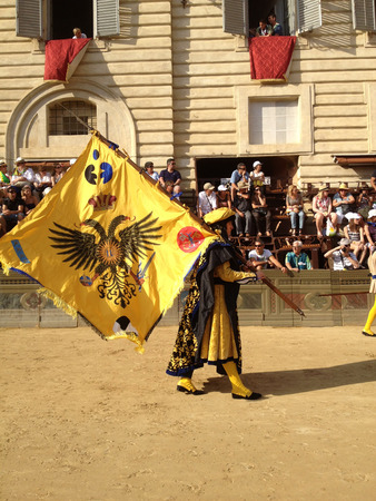 Siena, Italy - July 02, 2012: tourists watching the colorful and fancy traditional costume parades at the horse race, Palio di Siena, held in medieval square Piazza del Campo twice a year in Siena.のeditorial素材