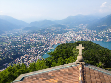 Cross on church rooftop and Top View of Lugano Lake and city from top of Monte San Salvatore with mountain panoramic landscape towards the Italy and Switzerland Border, Ticino, Switzerland, Europeの写真素材