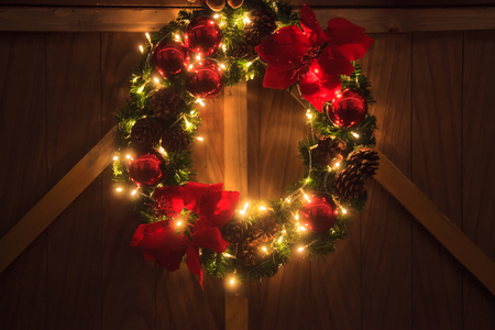 Sparkling Illuminated Christmas Garland Wreath at night of Christmas Eve. Christmas decoration with blinking warm golden incandescent light on wooden wall. Christmas, New Year, Holiday, Event conceptの写真素材