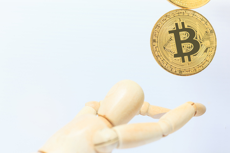 wooden robot model stops falling Bitcoin cryptocurrency token on white background. Investment, Currency Uncertainty, Risk and Reward, Exchange Medium, Fluctuation, Financial Tool, Robot System Conceptの写真素材