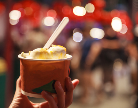 Fresh traditional sweet coconut milk tropical ice cream bowl on night food market background. Healthy sweets, summer dessert, indulgence, snack, nutrition, food, cuisine, gourmet and appetizer conceptの写真素材