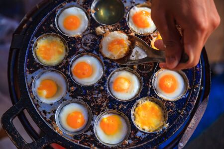 Traditional Thai Street Fast Food, quail eggs cooked in heating mantle (hot indented frying pan). Asian Cuisine, Delicacy, Culture, Cooking, Snack Food, Indulgence, Nutrition and Gourmet concept.の写真素材