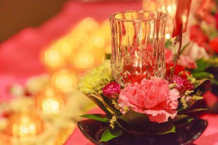 Lighting Candle and Offering Fresh Blossoming Flowers before Buddha Image believed to bring good merits to sincere Buddhist prayers. Religion, Buddhism, Faith, Spirituality, Belief and Ritual conceptの写真素材