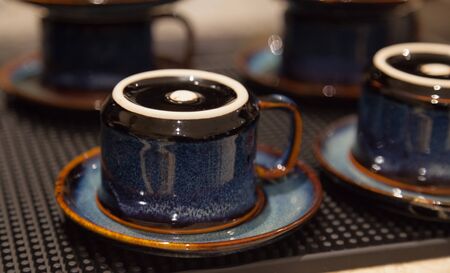 Clean dried hygienic vintage coffee drinking cups placed upside down on earthenware saucers, ready to use. Liquid serving containers used in Food and Drink Catering Service Industry, Utensils concept.の写真素材