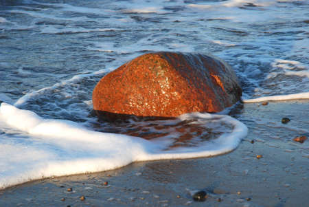 Red stone on a sunlit beachの写真素材