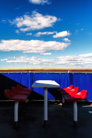 Red chairs on a blue background on the ferry in the springの写真素材
