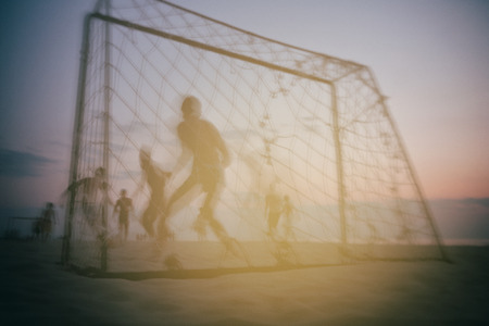 Boys play football at the gate on the summer beach at sunset. Art.の写真素材