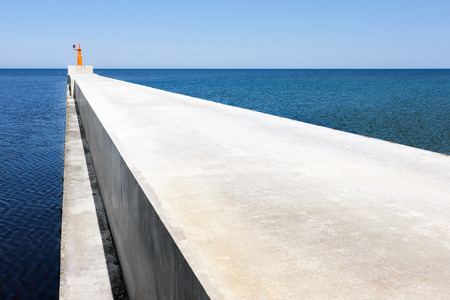 Concrete cape lighthouse triangle goes into the blue sea. Baltic seaの写真素材