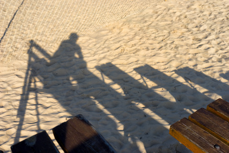 The shadow of the viewer on a bench on the beach at the net. Baltic seaの写真素材