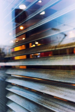 City life is reflected in the window of a cafe with linear shutters. Riga